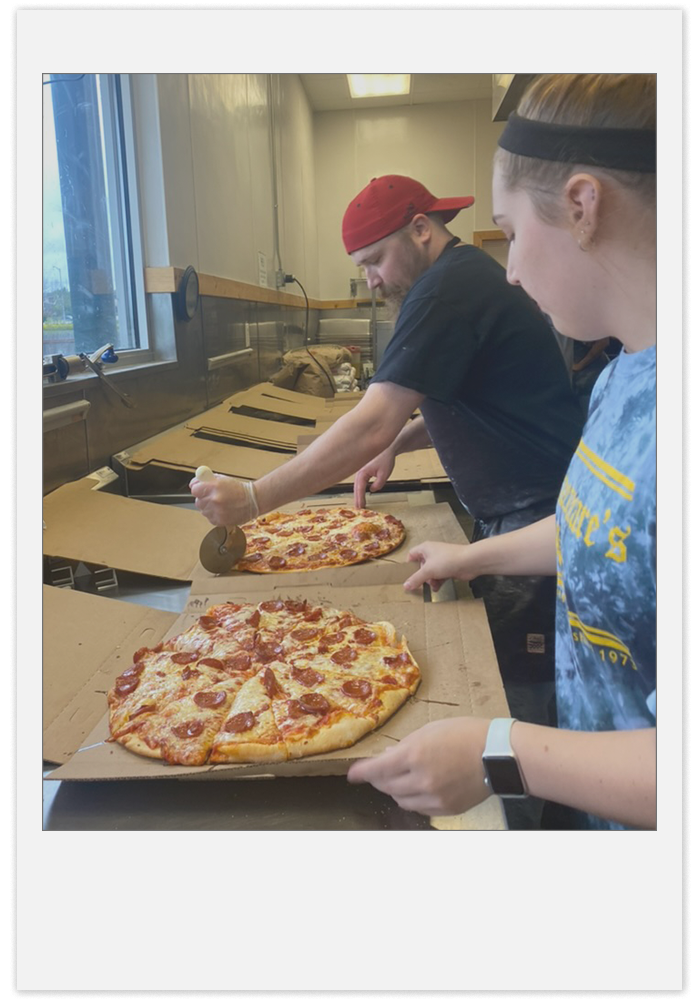 Slicing pizzas that are lined up in boxes